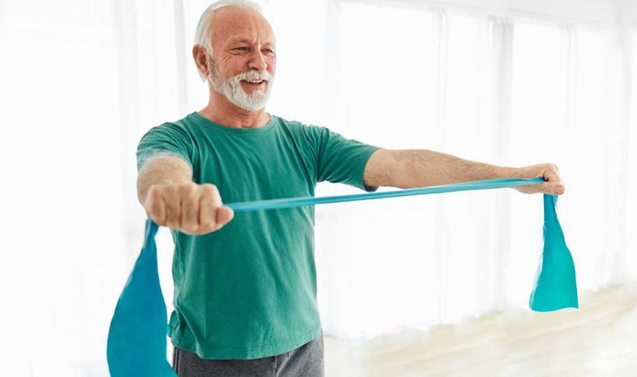 Stariji muškarac u svijetloj prostoriji rasteže elastičnu traku