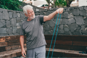 Stariji muškarac vježba s elastičnom trakom na otvorenom