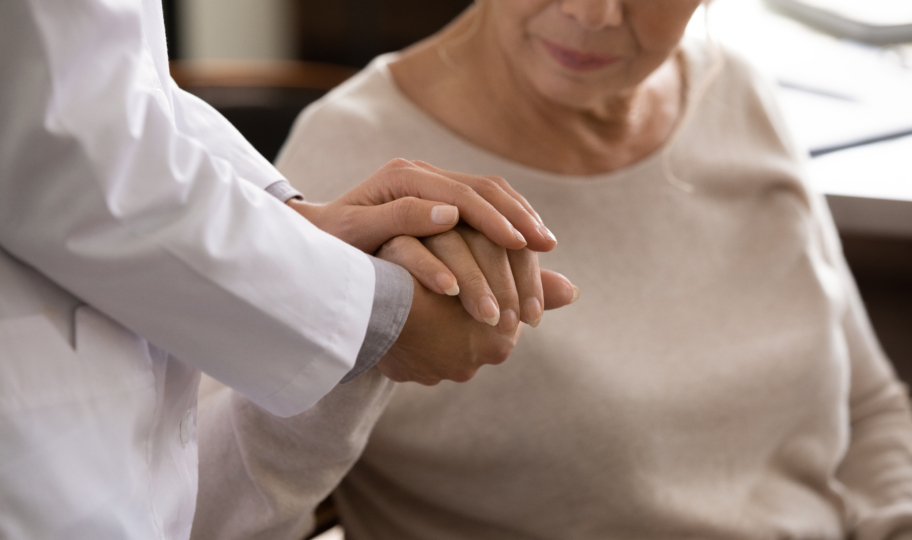 krupni kadar liječnice koja drži stariju pacijenticu za ruku, podrška