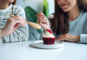 dvije prijateljce zajedno jedu crveni cupcake