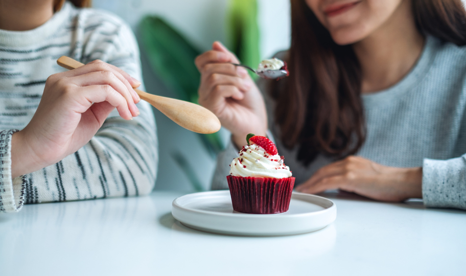 dvije prijateljce zajedno jedu crveni cupcake