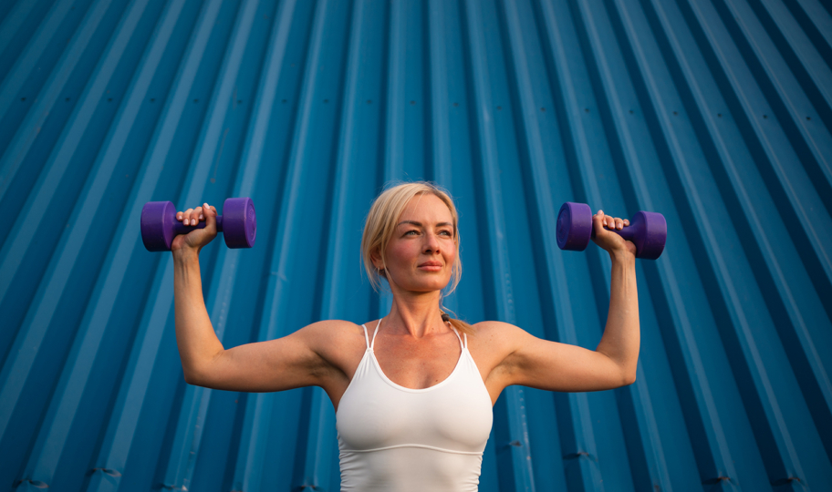 žena s bučicama u rukama vježba na otvorenom