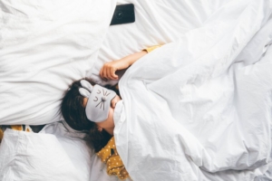 djevojčica spava u krevetu s maskom za spavanje