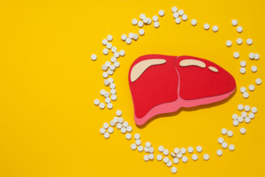 apirnati modle jetre okružen bijelim tabletama na žutoj podlozi