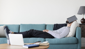 muškarac pod stresom leži na kauču s knjigom preko lica
