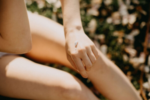 žena u kupaćem kostimu nanosi kremu s SPF-om na ruku