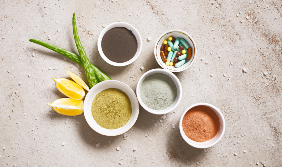 različiti sumplementi i dodaci prehrani u zdjelicama na sivoj podlozi