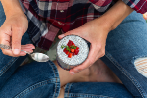 žena sjedi na podu i jede chia puding s jagodama