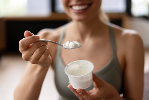 nasmijana žena u majici bez rukava jede grčki jogurt