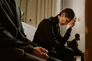 starija žena sjedi u crkvi na pogrebu i tuguje