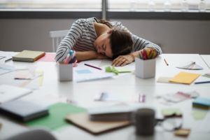 iscrpljena mlada žena spava za uredskim stolom