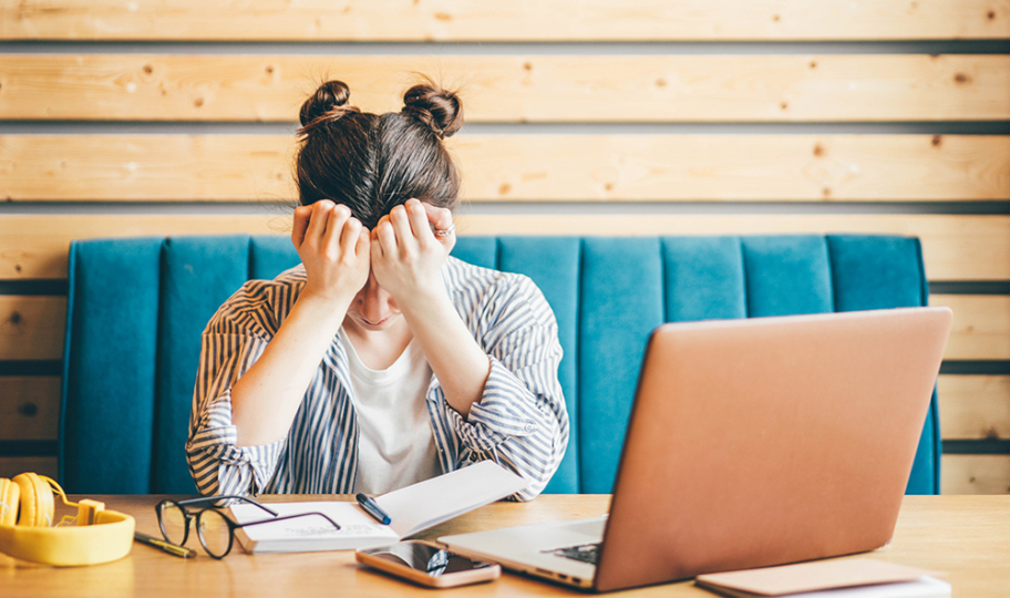 umorna mlada žena pokušava raditi za laptopom