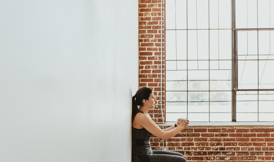 izometričke vježbe za snižavanje tlaka. žena izvodi čučanj na zidu