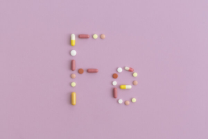 simbol željeza ispisan tabletama na rozoj podlozi, simbolizira suplemenate željeza