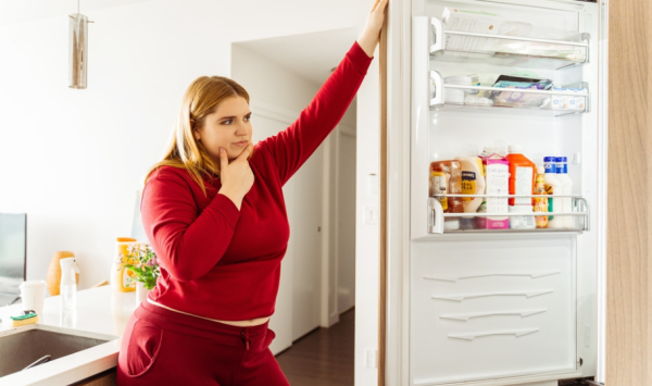 debela žena gleda u otvoreni frižider
