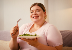 pretila nasmijana žena drži tanjur salate