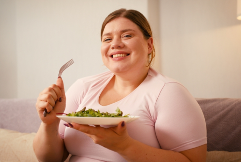 pretila nasmijana žena drži tanjur salate