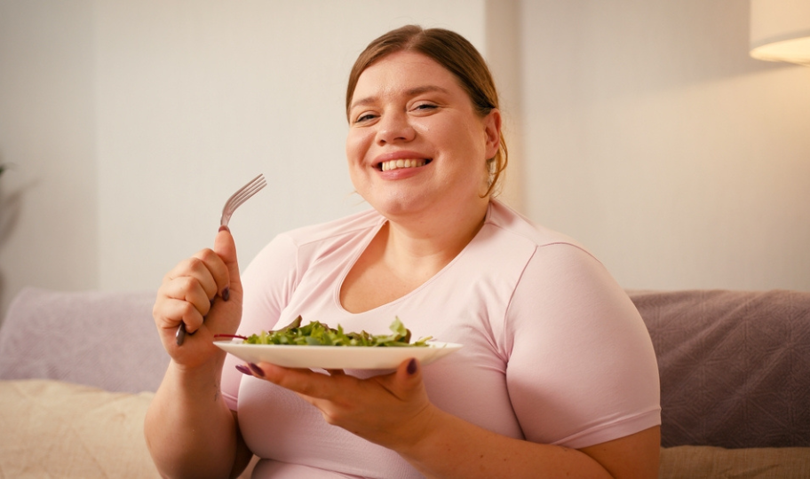 pretila nasmijana žena drži tanjur salate