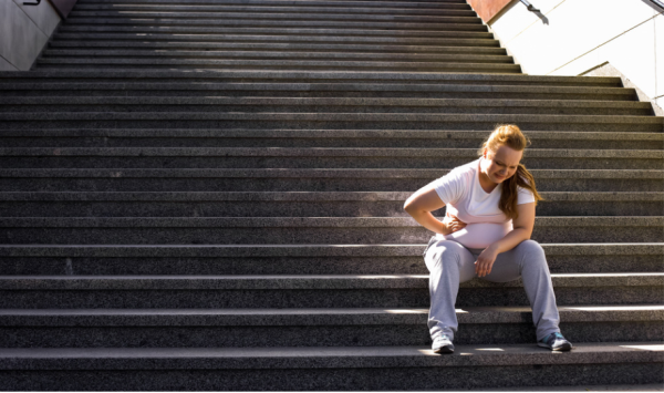 debela žena sjedi na stepenicama, mučno joj je