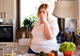 debela žena u kuhinji pije čau vode