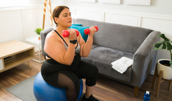 pretila mlada žena vježba kod kuće s bučicama