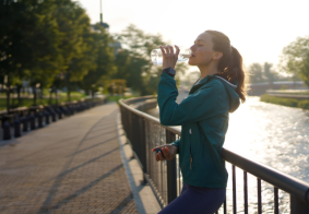 mlada žena pije vodu uz rijeku nakon treninga