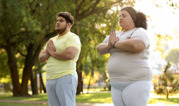 pretili mladi par meditira u prirodi