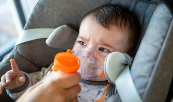 beba u auto sjedalici s inhalatorom na licu