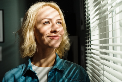 žena gleda u dnevno svjetlo kroz prozor