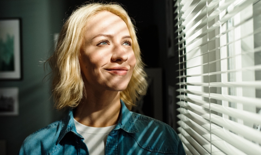 žena gleda u dnevno svjetlo kroz prozor